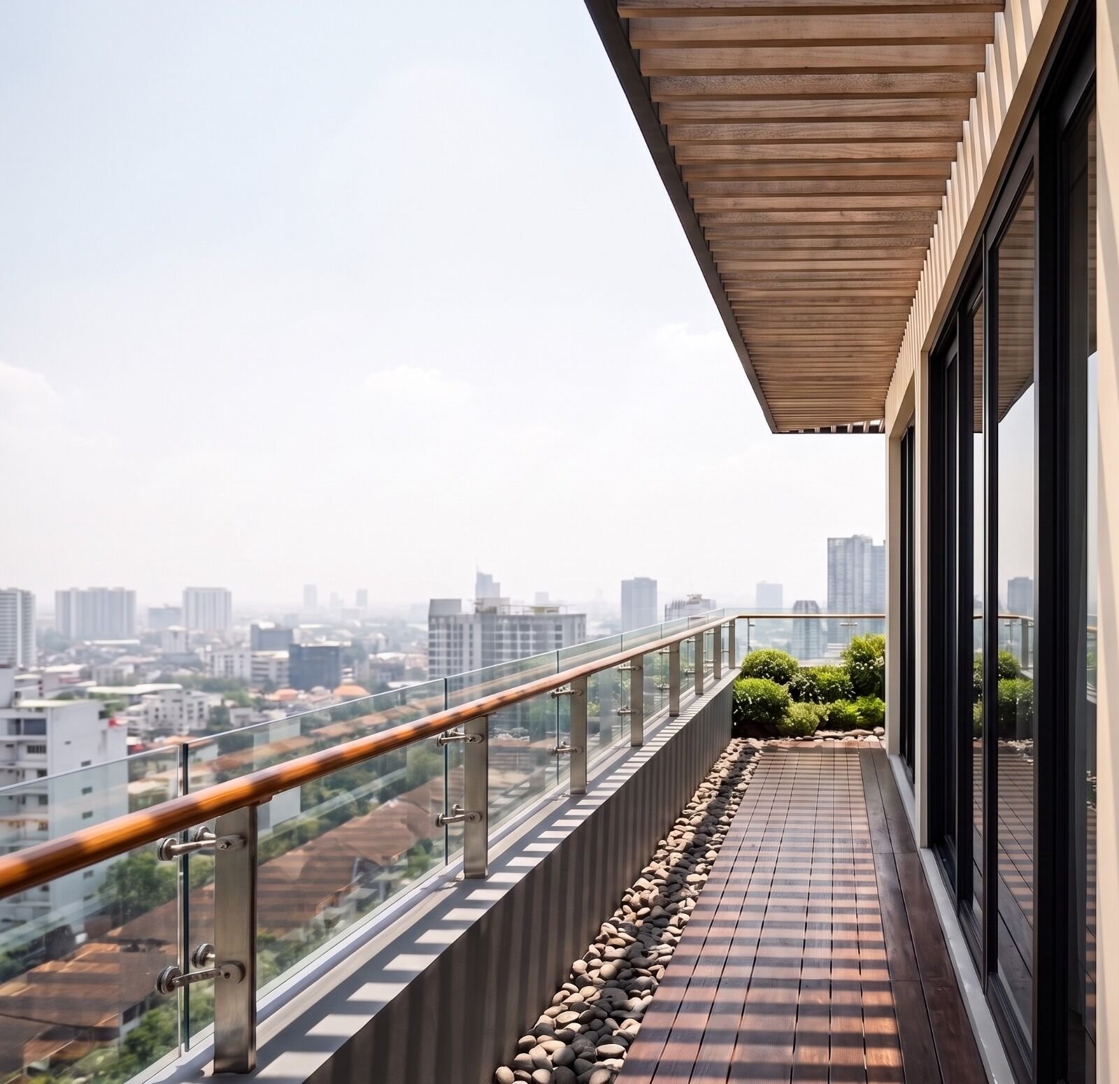 Balcón residencial con baranda de vidrio, piso de madera y vista a la ciudad